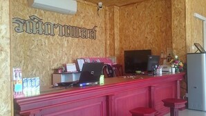 Een houten interieur met een rode bargedeelte, twee barkrukken, een laptop, een televisie en een beveiligingscamera aan de muur.