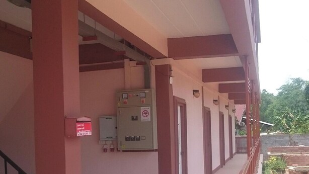 Een gebouw met een rood-wit kleurenschema, met een overdekte gang voorzien van een plafondlamp en elektrische panelen.