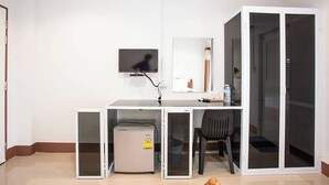 Een kamer met een bureau, een stoel, een televisie en een koelkast.