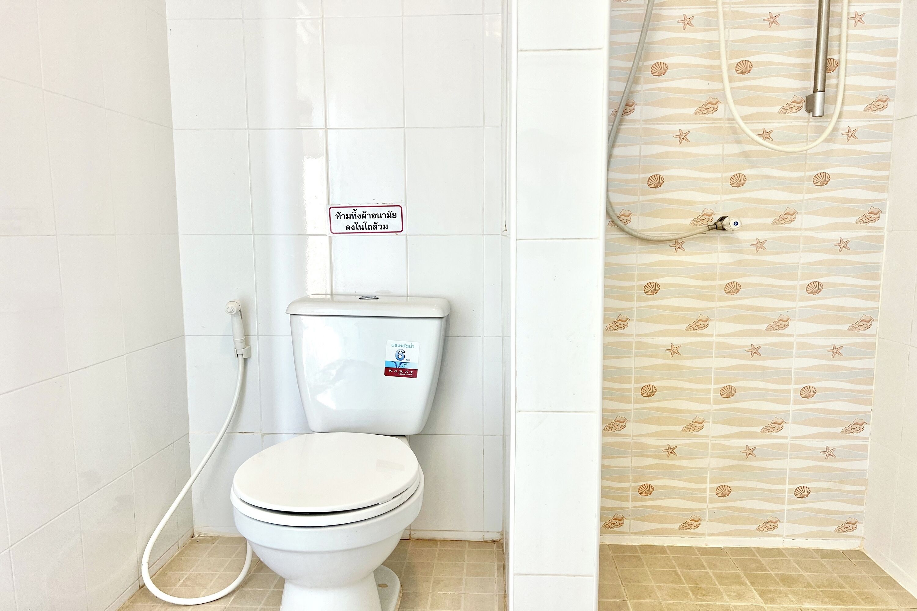 Kylpyhuone, jossa on wc, suihku ja kyltti thaiksi.