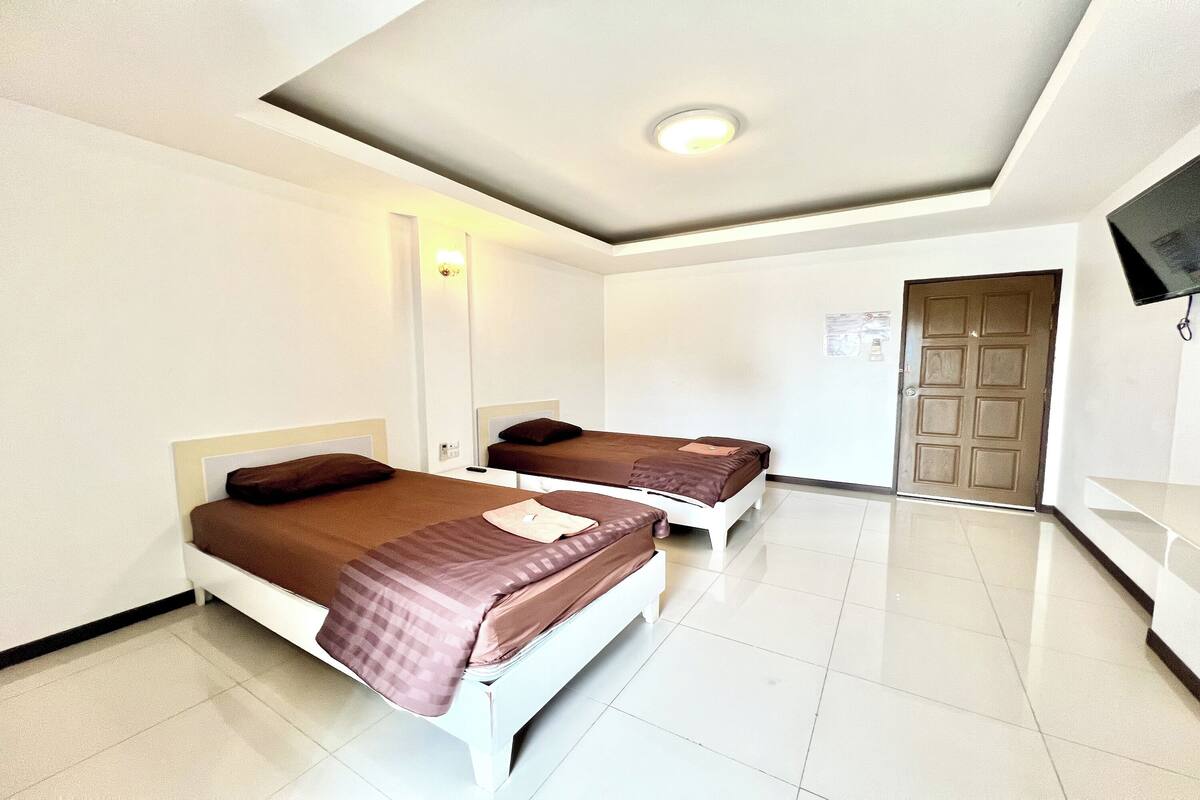 Una habitación de hotel con dos camas, un televisor de pantalla plana y una puerta.