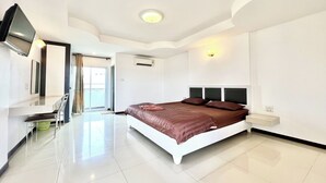 A modern bedroom with a large bed, a TV mounted on the wall, and a bright ceiling light. - Grand Place Resort (Udon Thani)