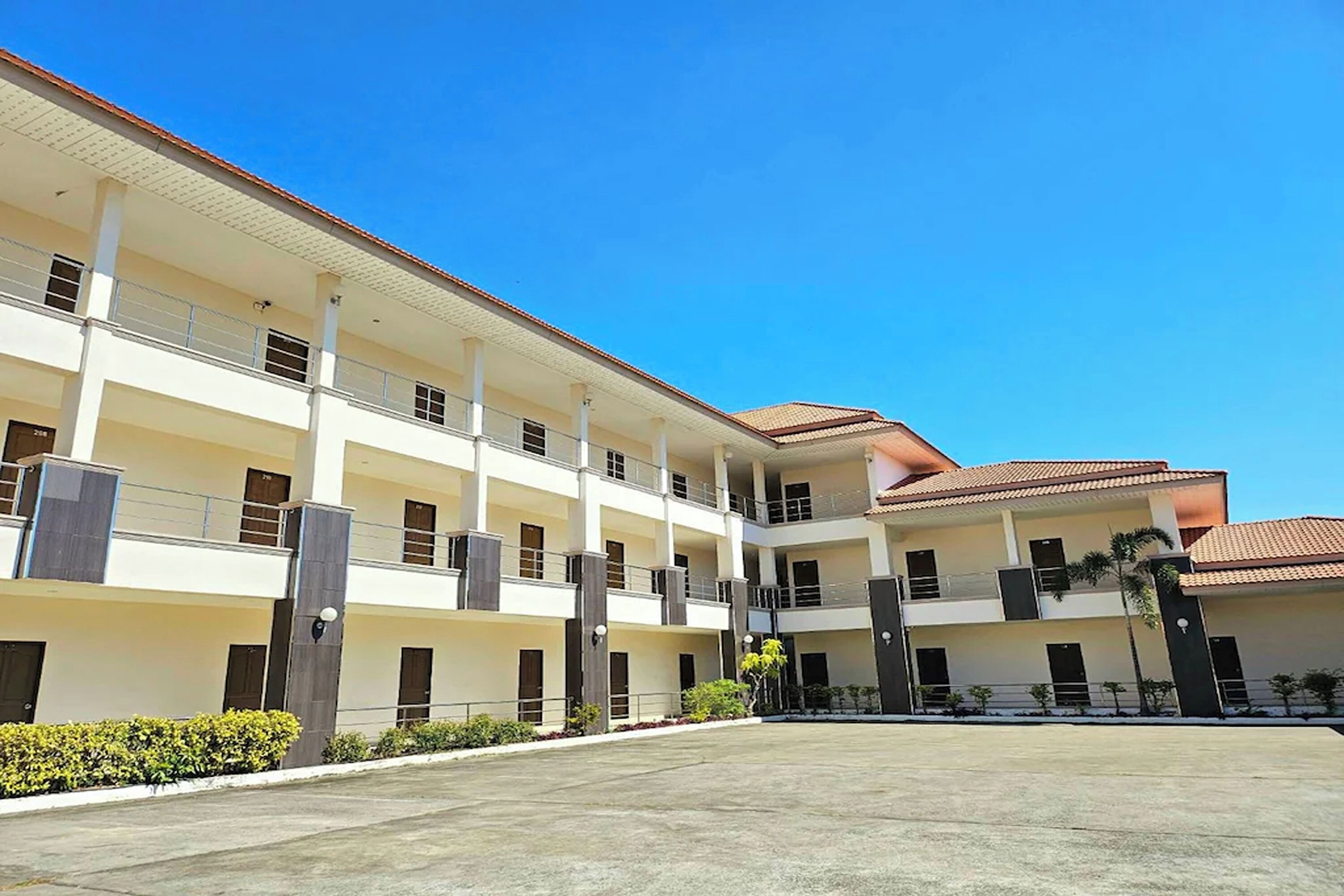 A multi-story hotel with a central courtyard, balconies, and a tiled roof.