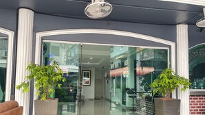 A hotel entrance with glass doors, potted plants, and a ceiling fan. - W-9 Hotel (Pattaya)