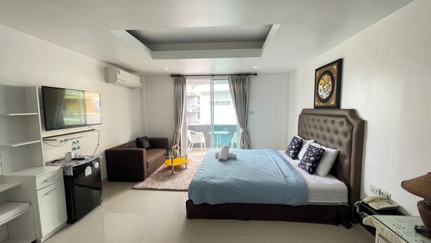 A modern hotel room with a bed, a TV, a desk, and a balcony with a view. - W-9 Hotel (Pattaya)