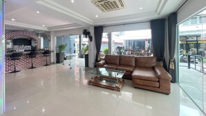 A spacious living area with a leather sofa, a glass coffee table, and a brick-patterned bar area. - W-9 Hotel (Pattaya)