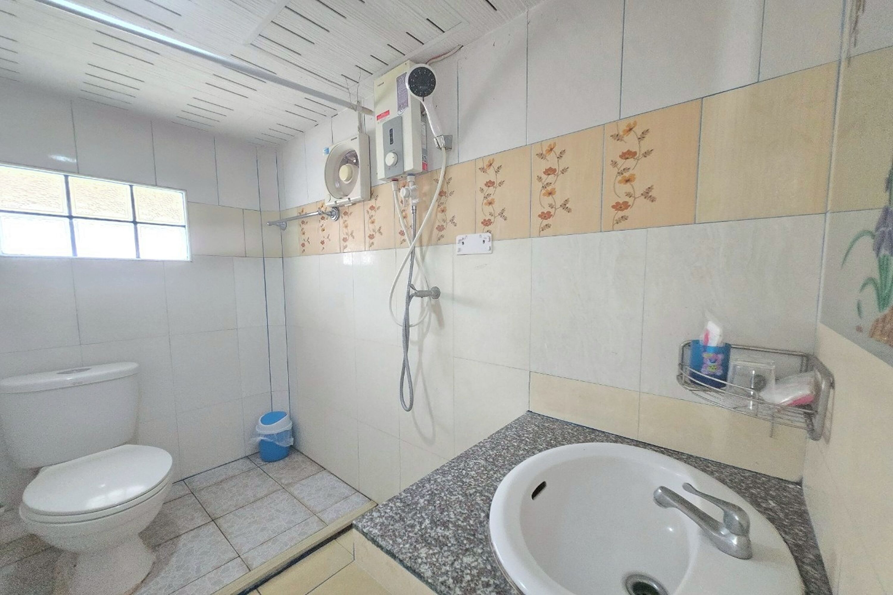 Ein Badezimmer mit Toilette, Waschbecken, Dusche und gefliesten Wänden.