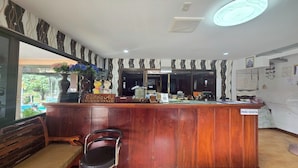A reception area with a wooden counter, a bench, and a chair. - Phaiboon Hotel & Resort (Pak Chong)