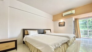 A hotel room with two beds, a nightstand, a wall-mounted air conditioner, and a window with curtains. - New Place Resort (Udon Thani)