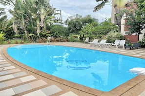 Una piscina al aire libre, sillones reclinables de piscina