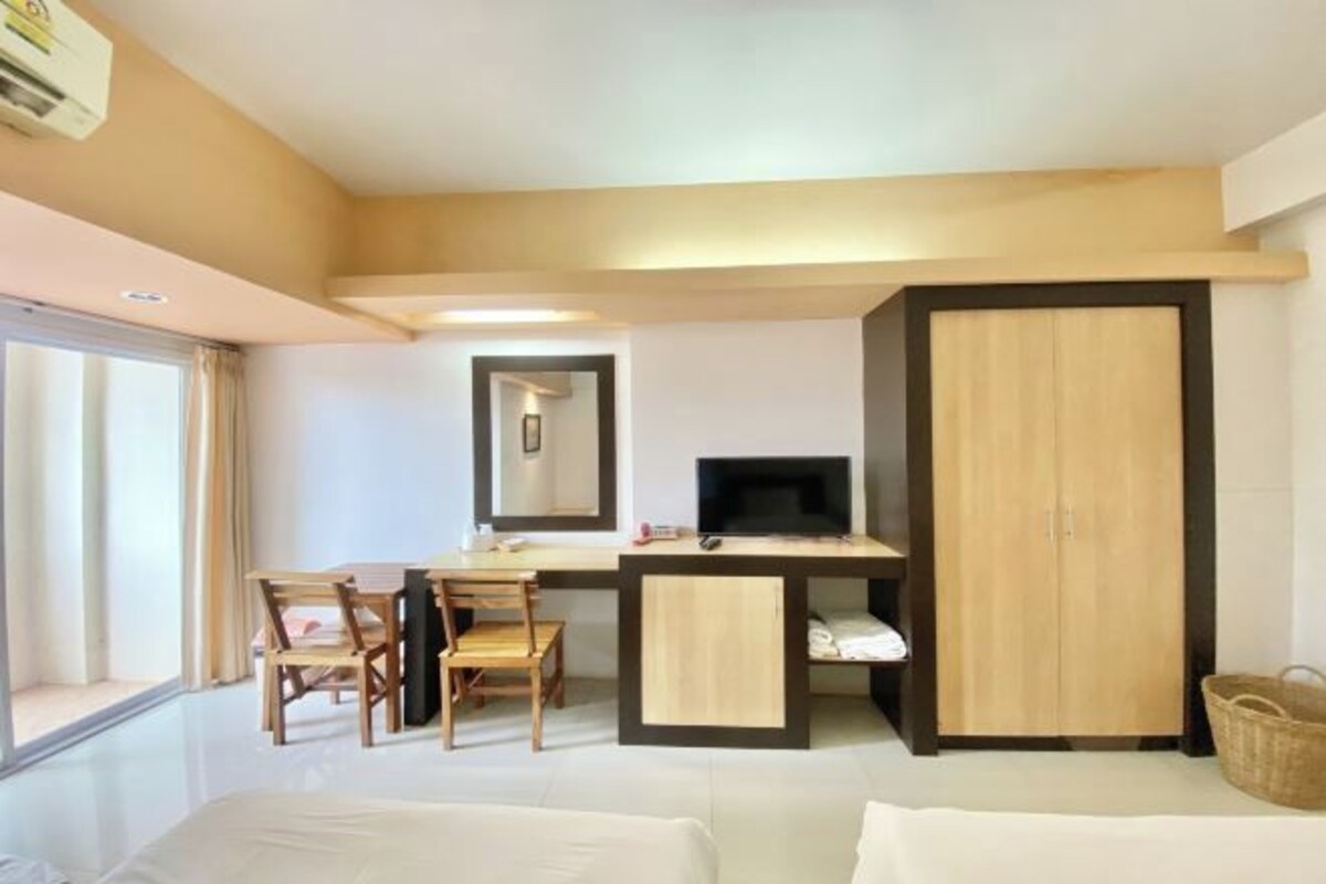A room with a bed, a desk with a chair, a TV, a wardrobe, and a window.