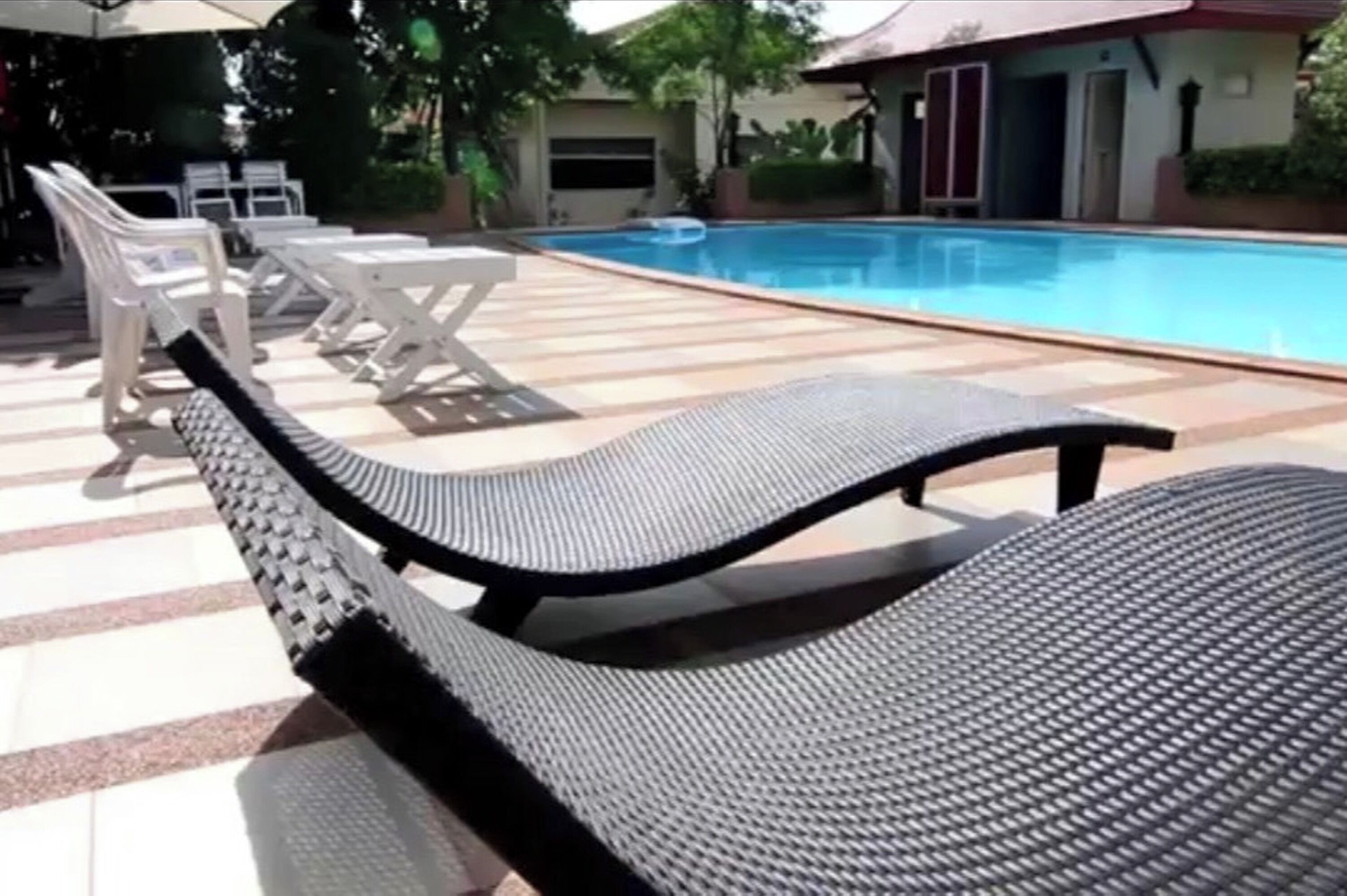 Un área junto a la piscina con sillones de descanso y una pileta.