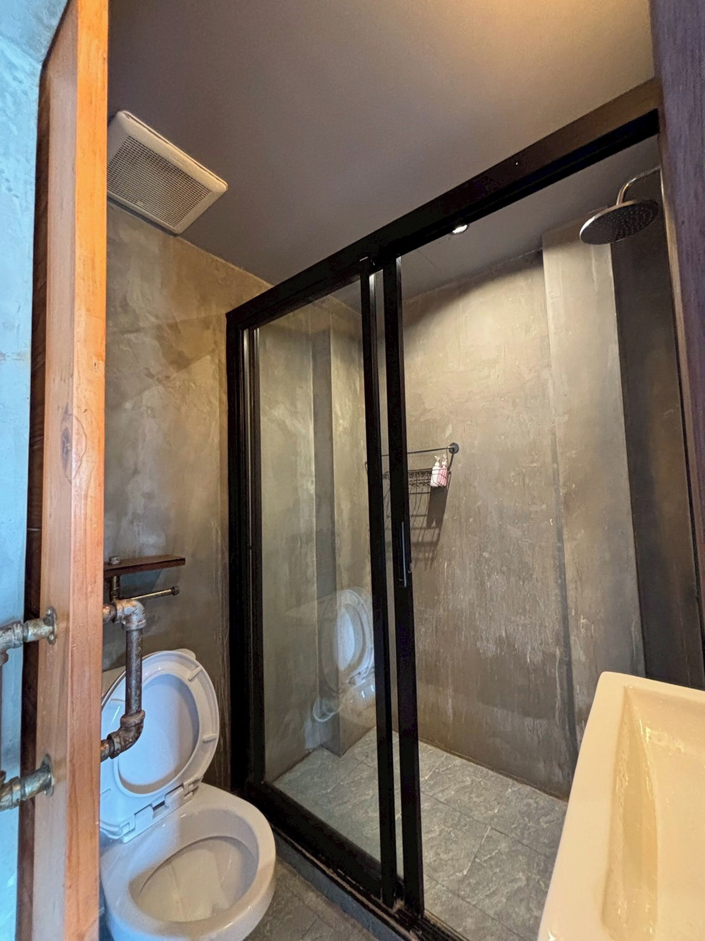 A bathroom with a glass-enclosed shower, a toilet, and a sink.