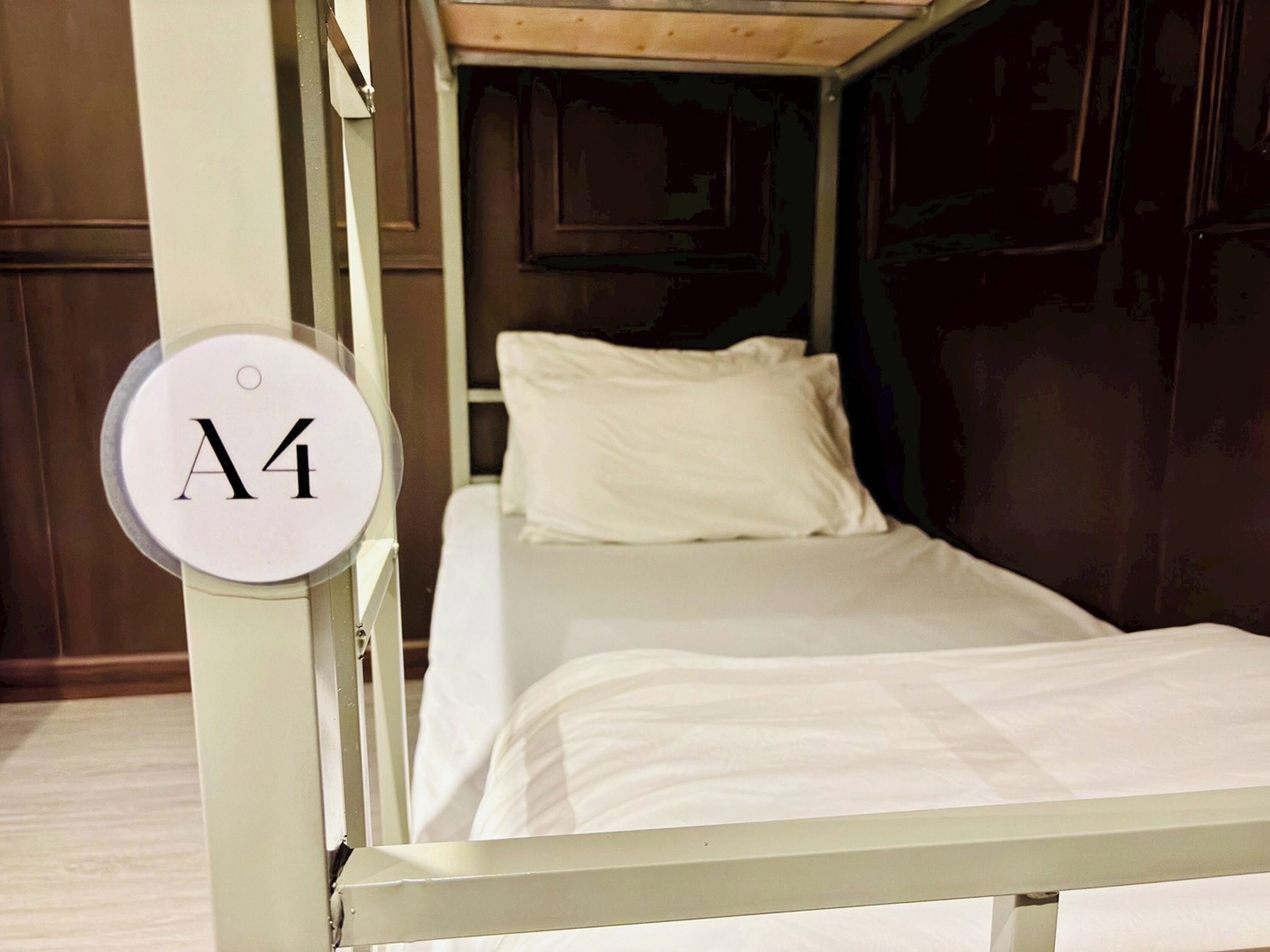 A single bed in a room with a white headboard and a circular sign with the number A4.