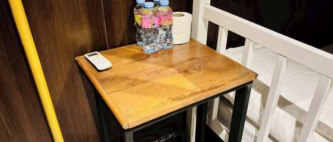 A wooden table with a white scale, bottles of water, and a roll of toilet paper.