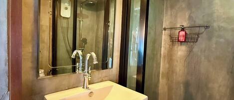 A bathroom with a white sink, a mirror, and a shower.