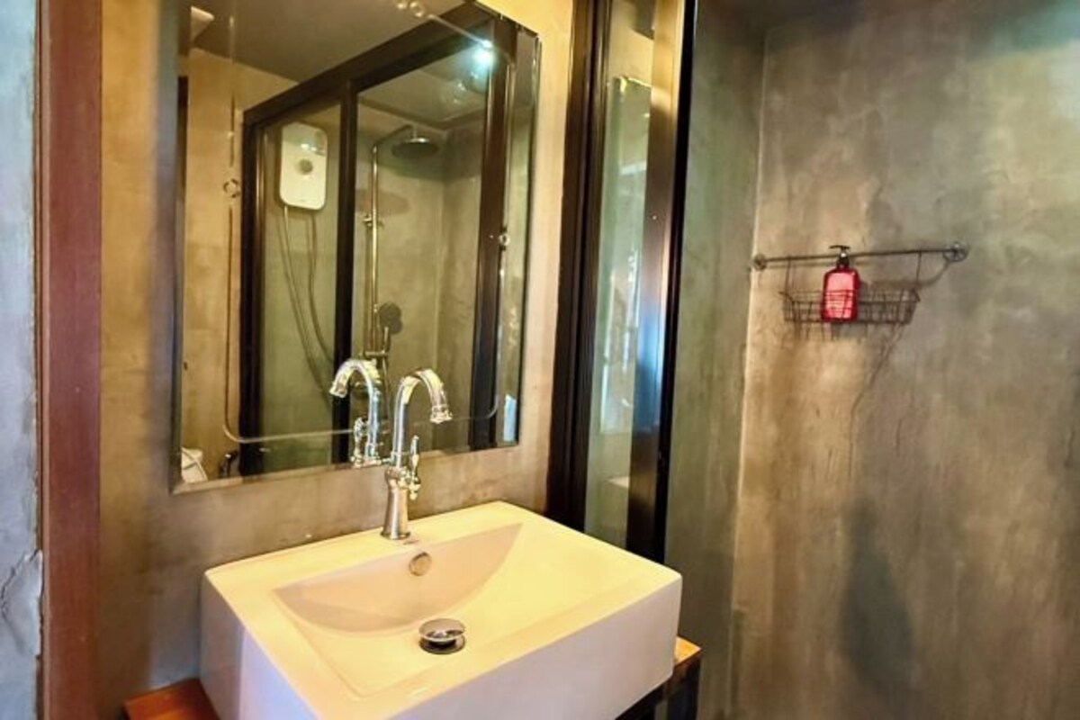A bathroom with a large mirror, a sink, and a shower.