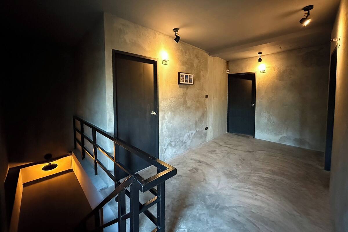 A hallway with two doors, each with a light fixture above. The walls are textured, and the floor is a light-colored material.
