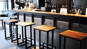 A modern bar area with a long counter, stools, and a variety of bar tools and bottles. - Sukhum Rajamangala-Phatthanakan Rooms (Bangkok)
