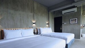 A hotel room with two beds, a concrete wall, and a door. - Sukhum Rajamangala-Phatthanakan Rooms (Bangkok)