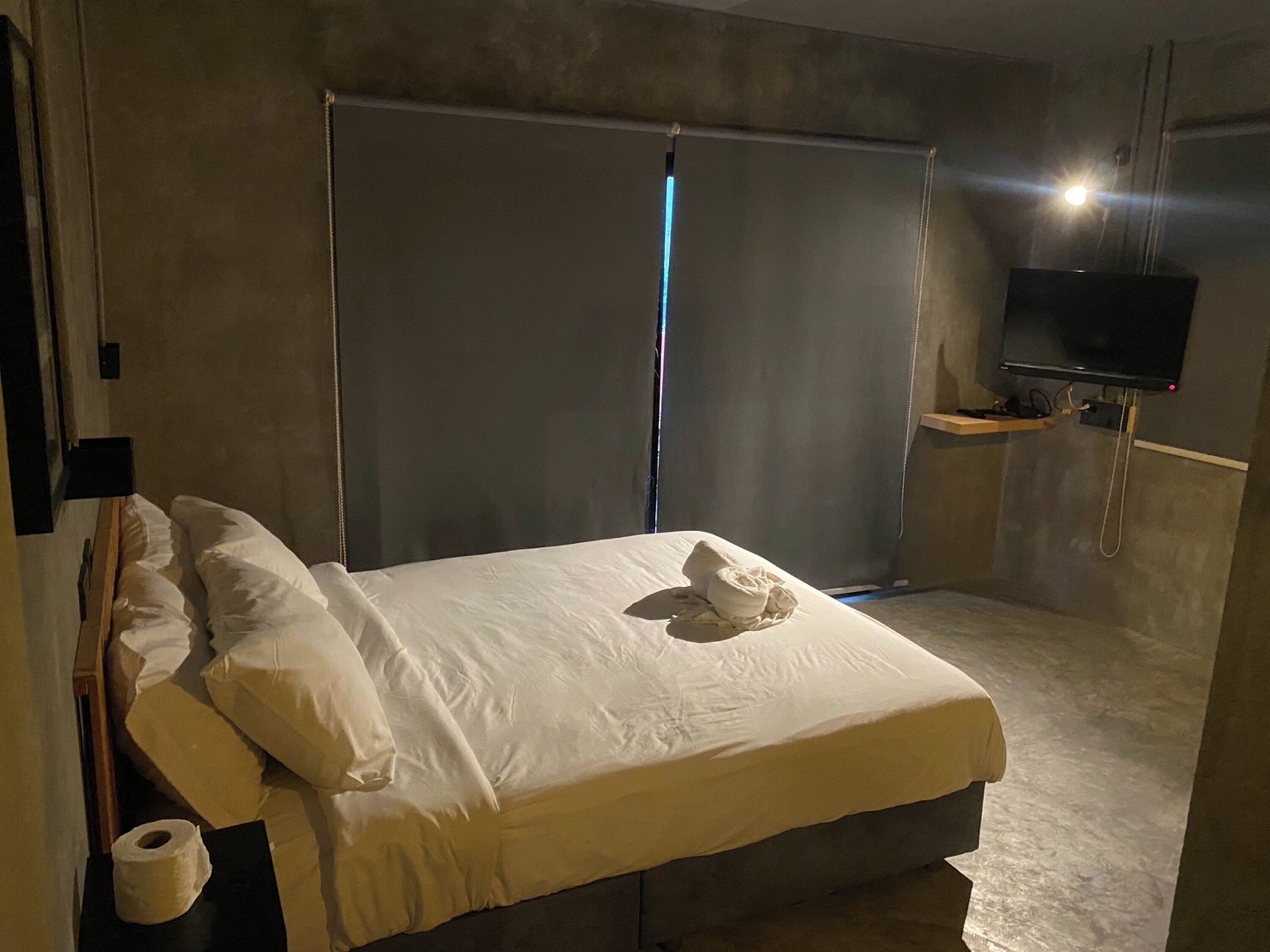 A hotel room with a bed, a television, and a large sliding door.