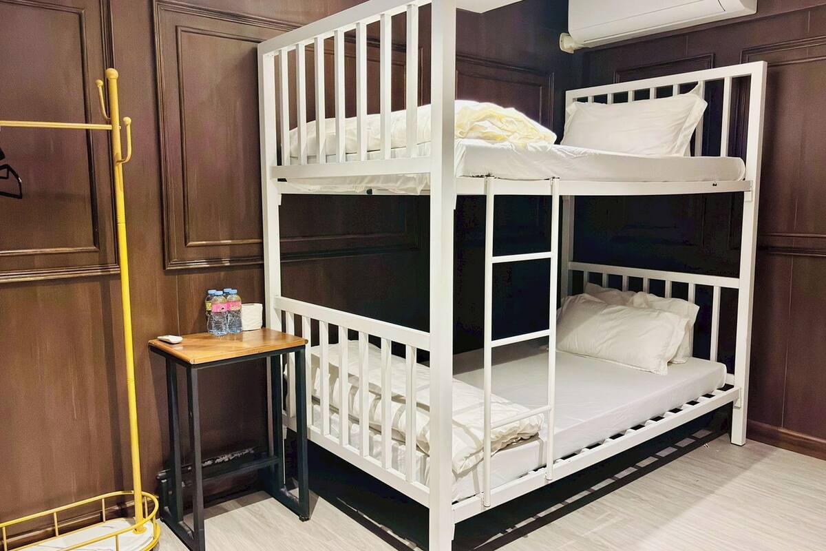 A bunk bed with a small table and bottles beside it.