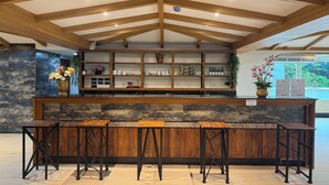 A reception area with a wooden reception desk, multiple bar stools, a stone wall, and a ceiling with exposed beams. - Eastan Golf View Chiangmai (Chiang Mai)
