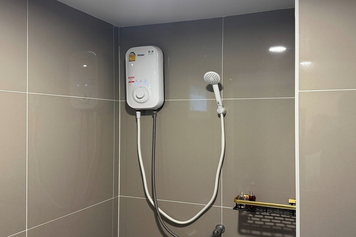 A modern bathroom with a built-in shower unit, including a handheld showerhead and a control panel.