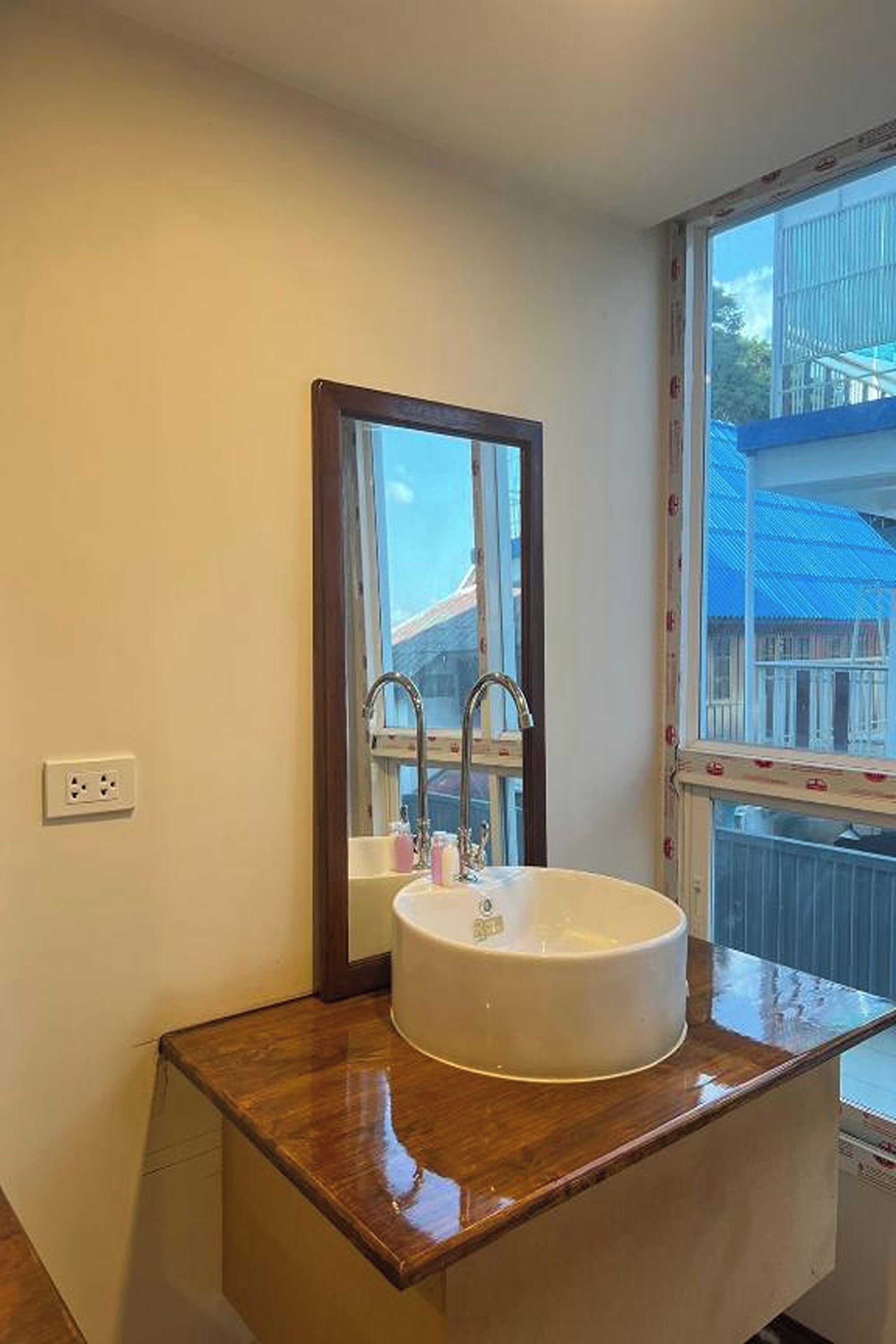 A bathroom with a round sink, a mirror, and a window with a view of buildings.