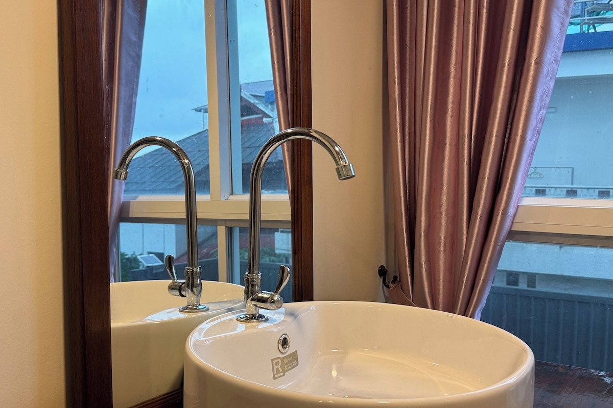 Un baño con dos lavamanos y una ventana con cortinas.