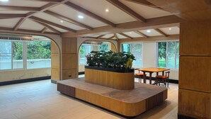A spacious room with a wooden ceiling, large windows, and a central planter with plants. - Eastan Golf View Chiangmai (Chiang Mai)