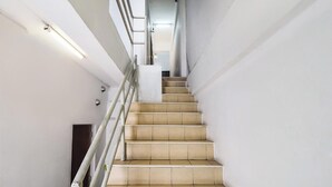 Un escalier moderne avec des murs blancs et une rampe en métal.