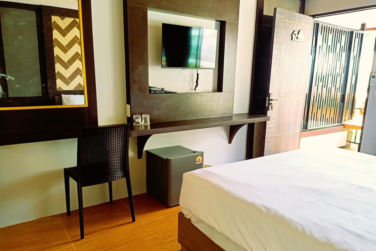 A hotel room with a bed, a desk, a chair, a television, and a wardrobe.