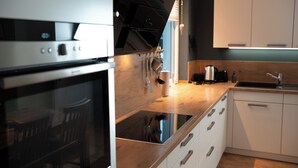 A modern kitchen with stainless steel appliances, wooden countertops, and white cabinetry. - "Glücklich am Harz" dog-friendly vacation home with garden and fireplace (Goslar)