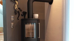 A modern room with a wood-burning stove, a small decorative lizard, and a wooden floor. - "Glücklich am Harz" dog-friendly vacation home with garden and fireplace (Goslar)