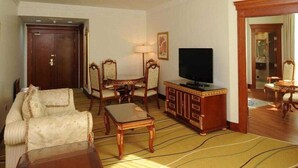 A hotel room with a sofa, armchairs, a TV, a cabinet, and a mirror. - Holiday International Hotel Bur Juman By Sunday (Dubai)