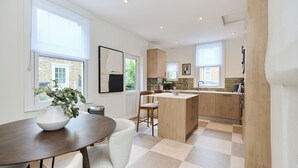 Una cocina moderna con una isla central, armarios de madera y una zona de comedor con mesa y sillas.