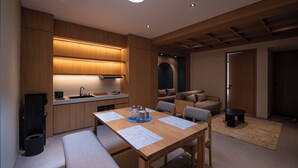 A modern kitchen with wooden cabinetry, a dining area with a table and chairs, and a cozy seating area with a sofa and armchairs. - Amani Suites Yogyakarta (Yogyakarta)