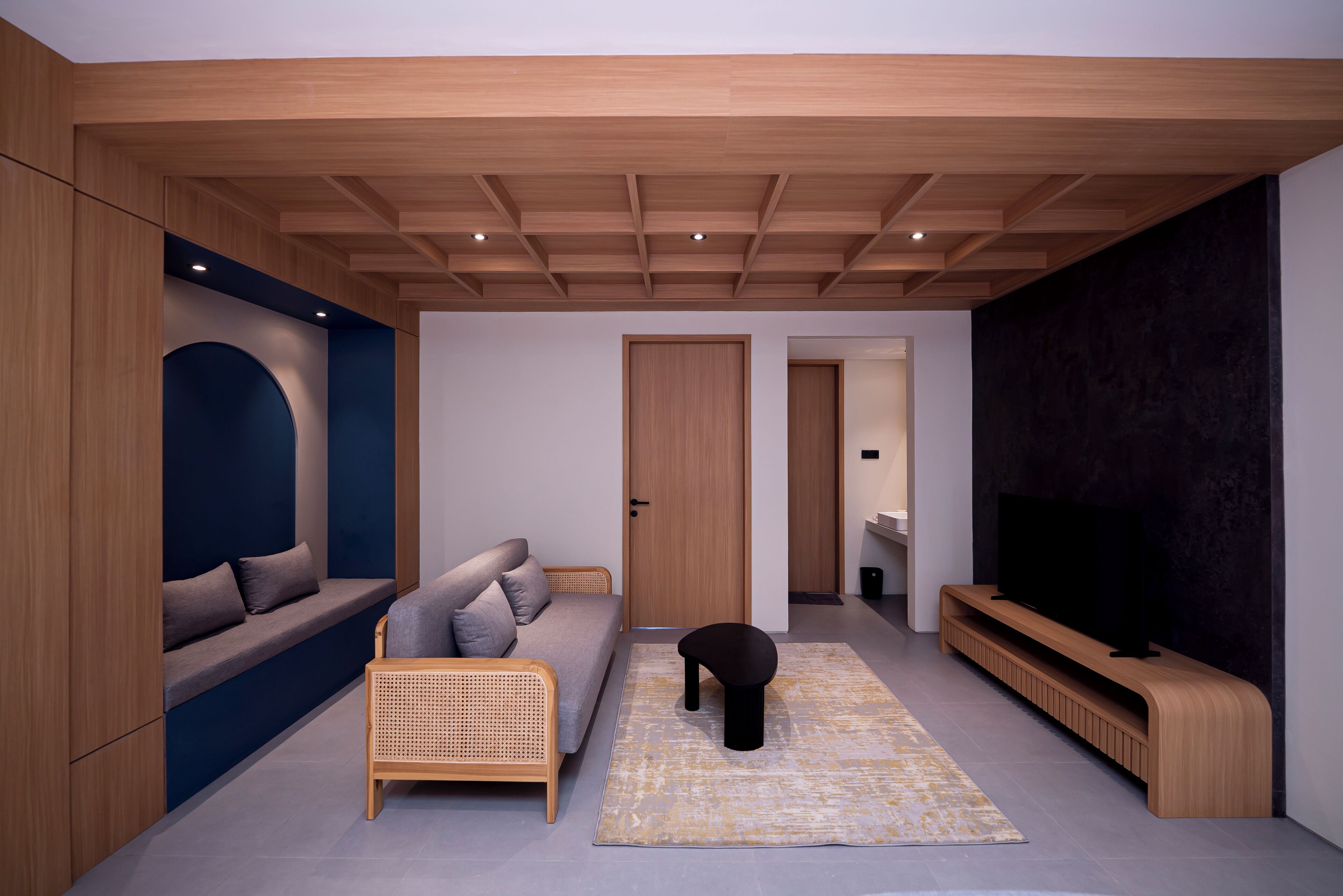 A modern living room with a sofa, a small table, a television, and a dark accent wall.