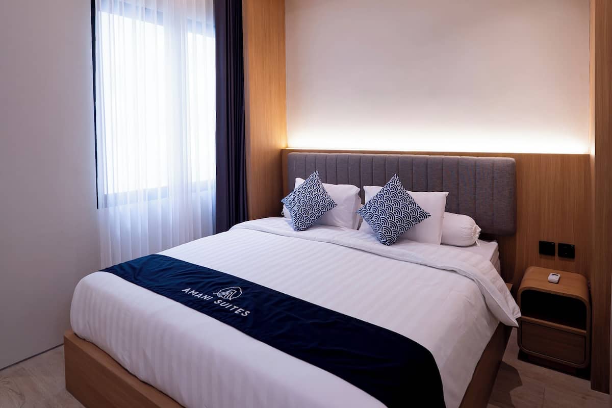 Una habitación de hotel moderna con una cama grande, una mesita de noche y un velador.