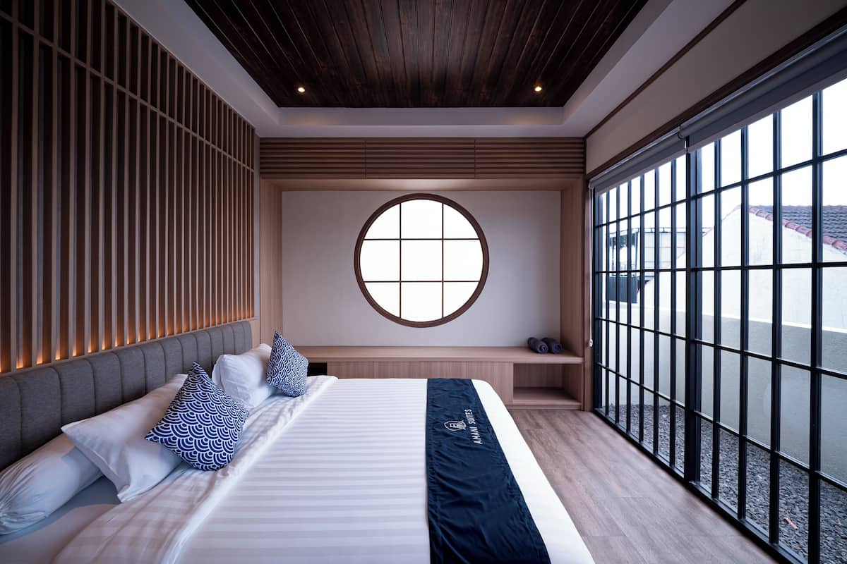 Una habitación de hotel moderna con una cama grande, un ventanal redondo y vistas al exterior.