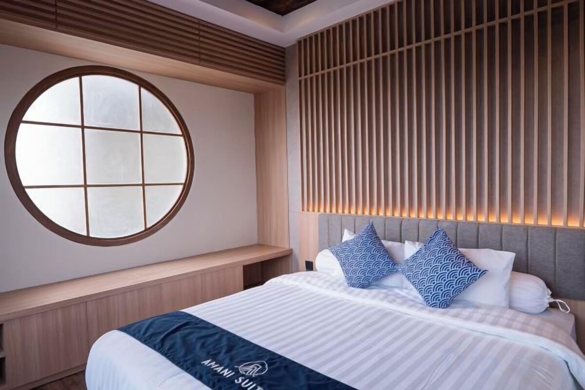 Habitación de hotel con una cama grande, un ventanal redondo y un diseño de pared con listones.