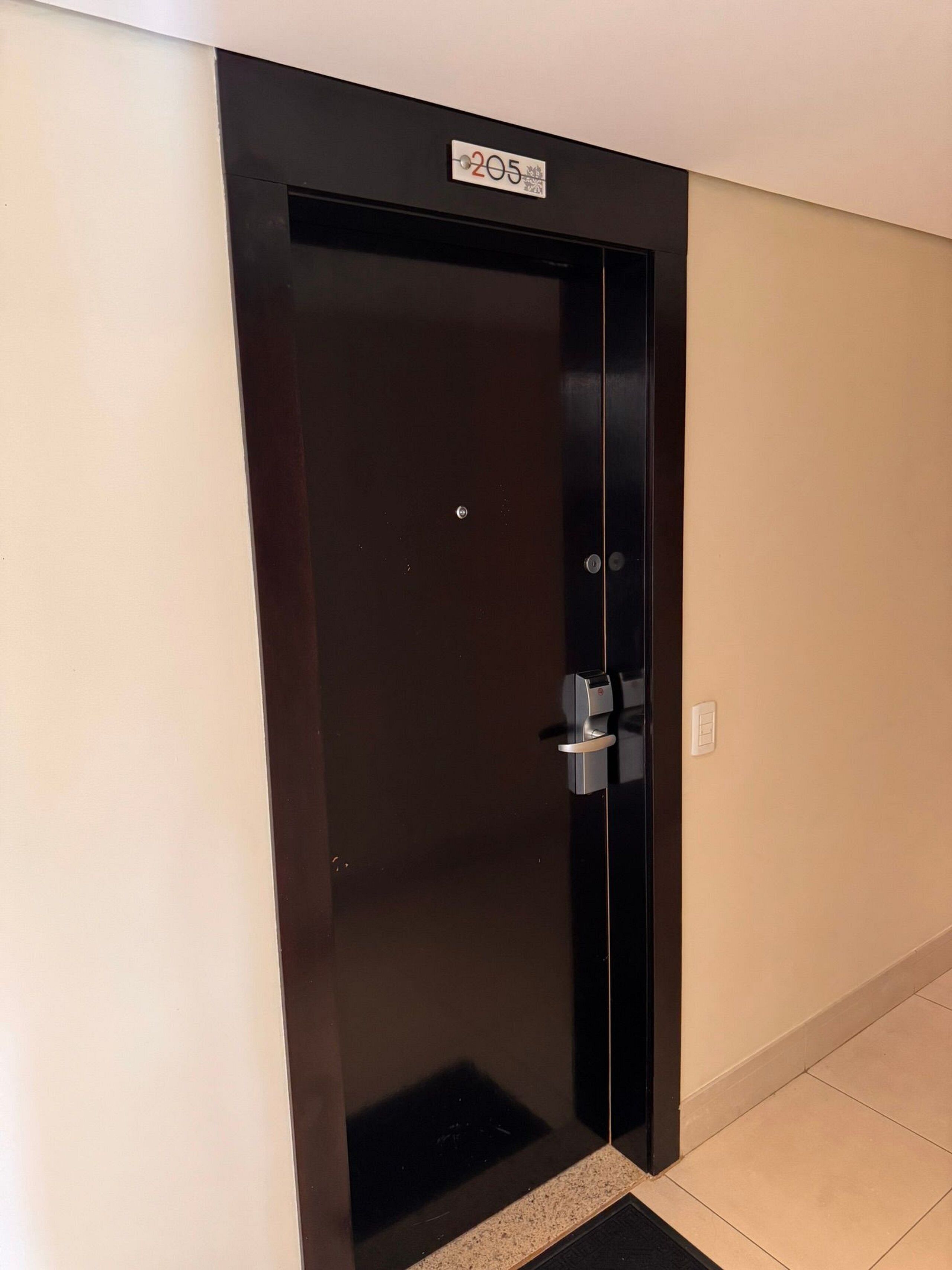 Een donkergekleurde liftdeur met een bord erboven dat vloernummer 205 aangeeft.