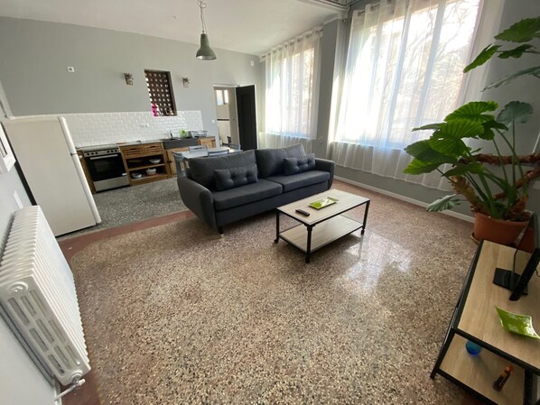 A living room with a sofa, coffee table, and a potted plant.
