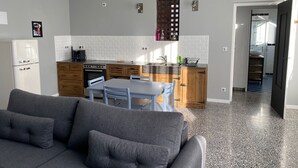 A modern kitchen with white subway tiles, wooden cabinets, and a dining area with a grey sofa and blue chairs. - Self-contained apartment in village house (Saint-André-de-Sangonis)