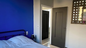 A bedroom with a bed, a door, and a wall-mounted light fixture. - Self-contained apartment in village house (Saint-André-de-Sangonis)