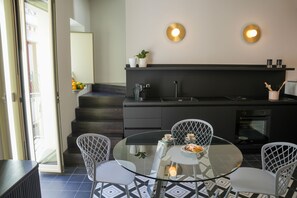 Una cocina moderna con una mesa de comedor de vidrio, sillas blancas y una encimera negra.