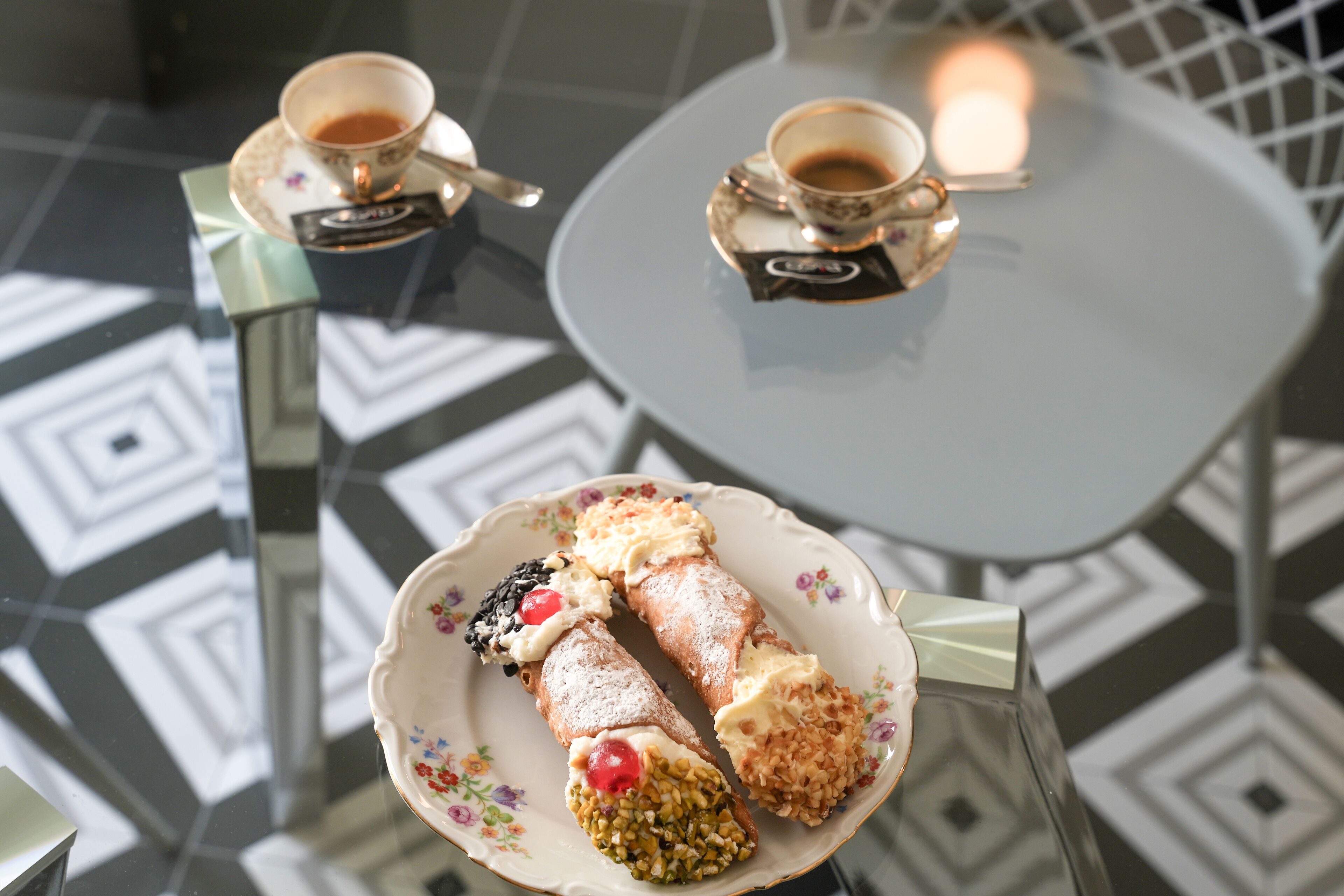 A table with two cups of coffee and a plate of pastries.