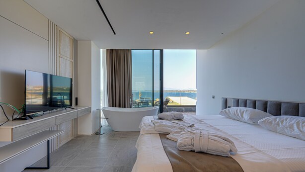 Una habitación de hotel moderna con una cama grande, televisión de pantalla plana, bañera y vista a la ciudad.