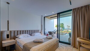 A modern hotel room with a large bed, a bedside table, a chair, and a view of the outdoors. - VENTO MARE ÇEŞME (Cesme)